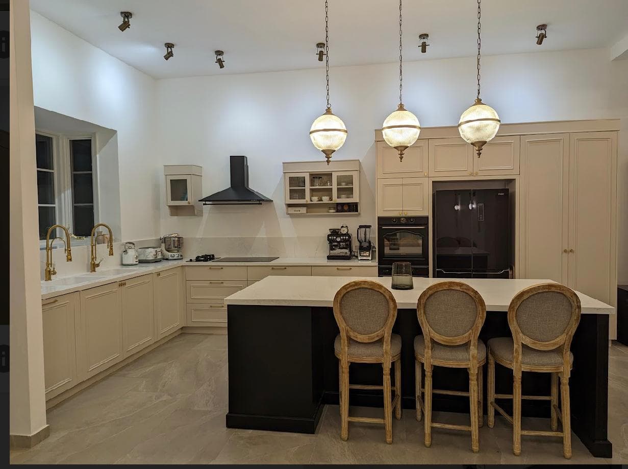 White kitchen with black marble island and gold lighting