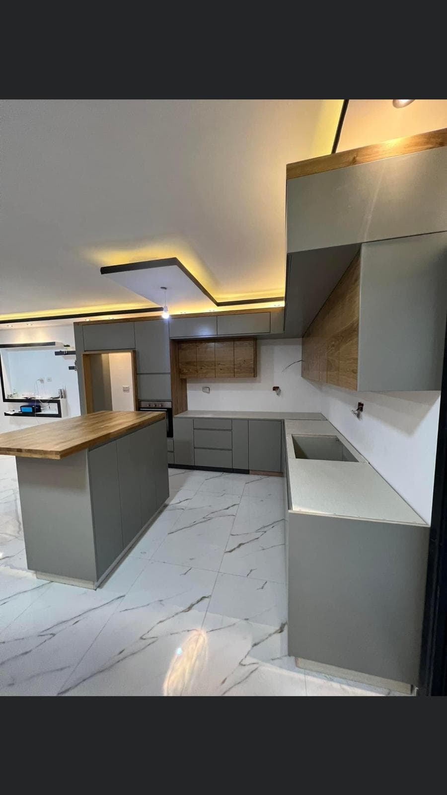 Modern kitchen with central island, grey stone, and black lighting